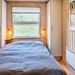 Schlafzimmer mit Bett, Fenster und Holzwand
