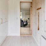 Flur mit Holzwand, Spiegel und Blick in Wohnzimmer mit Sofa.