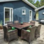 Außenbereich mit Tisch, Stühlen und Rattan-Sofa vor blauem Haus