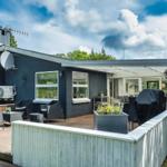 Ein Haus mit Terrasse, Sitzgelegenheiten und Grillplatz im Freien.