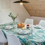 Runde Tisch mit Tischdecke, Stühlen und Frühstückszubehör unter Holzdecke.