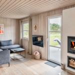 Wohnzimmer mit Sofa, Kamin und Blick auf die Terrasse.