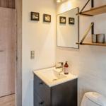 Badezimmer mit Waschbecken, Spiegel und Holzregalen an der Wand.