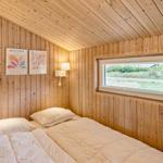 Schlafzimmer mit Holzwand und Fenster. Bett mit Kissen und Decke.
