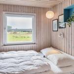 Schlafzimmer mit Holzwand, Fenster und Bett. An der Wand hängen Bilder und eine Pflanze.