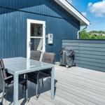 Terrasse mit Tisch, Stühlen und Grill. Blauer Holzaufbau und Holzdecke.