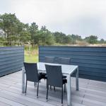 Terrasse mit Tisch, Stühlen und Liegestühlen. Blick auf Wald und Grasland.