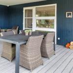 Terrasse mit Tisch, Stühlen, Grill und Holzstapel.
