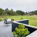 Terrasse mit zwei Stühlen und Blick auf grünes Feld und Bäume.