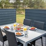 Terrasse mit Tisch und Stühlen für vier Personen, darauf Frühstückszubereitung.