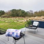 Terrasse mit zwei Stühlen und Tisch. Blick auf Grasland und Bäume.