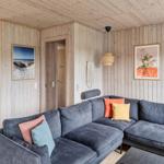 Wohnzimmer mit Ecksofa, Küchenbereich und Holzwandverkleidung.
