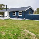 Ein blaues Haus mit Terrasse und Garten. Gartenmöbel und Sitzgelegenheit sind vorhanden.