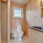 Badezimmer mit Toilette, Waschbecken und Dusche. Holzwände und Fliesenboden.