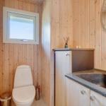 Badezimmer mit Holzwand, Toilette, Waschbecken und Spiegel