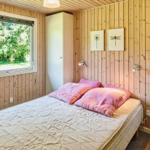 Schlafzimmer mit Holzwand, Bett und Fenster zum Grün.