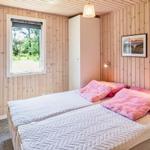 Schlafzimmer mit Holzwand, Bett und Fenster zum Garten.