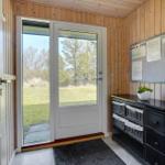 Eingangsbereich mit Glasfront, Holzwand und schwarzer Kommode mit Körben.