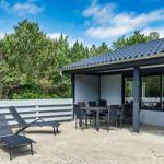 Terrasse mit Liegen und Tisch, angrenzend an modernes Haus mit Glasfront.