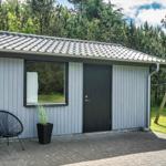 Moderne Hütte mit Terrasse, Schaukel und grünem Garten im Wald.