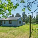 Ein kleines Haus mit grünem Garten und Bäumen im Hintergrund.
