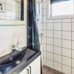 Badezimmer mit Dusche, Waschbecken und Spiegel