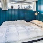 Schlafzimmer mit blauen Wänden, Bett mit weißer Bettwäsche und Fenster mit Blick auf Bäume.