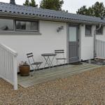 Wohnung mit Terrasse, Tisch und zwei Stühlen. Weiße Fassade, graue Tür und Dach.