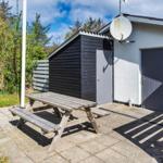 Außenbereich mit Picknicktisch, Garten und Holzhaus neben weißer Wand.