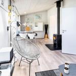 Wohnbereich mit Fernseher, Sessel und Kaminofen. Durchgang zur Schlafstube mit blauer Wand.