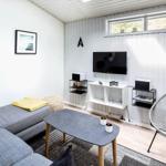 Wohnzimmer mit Sofa, Fernseher und Stuhl. Wand mit Bildern und Uhren.