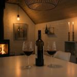 Tisch mit Weinglas und Flasche vor Kamin und Beleuchtung