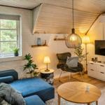 Ein Wohnzimmer mit blauem Sofa, Holztisch und Fernseher an der Wand.