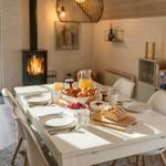 Esstisch mit Frühstück, Kamin und Fenster zur Außenterrasse.