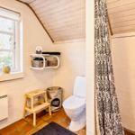 Badezimmer mit Dusche, Toilette und Fenster mit Blick nach draußen.