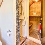 Bad mit Toilette, Dusche und Sauna mit Holzwand und Bank.