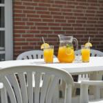 Weißer Tisch mit Stühlen und Getränken vor Backsteinmauer