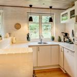 Küche mit Arbeitsfläche, Spüle, Kühlschrank und Fenster mit Blick auf Grün.