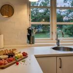 Küche mit Arbeitsfläche, Spüle und Fenster mit Blick auf Grünfläche.