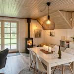Esszimmer mit Tisch, Stühlen und Kamin. Durchgangstür zum Garten.