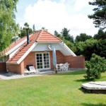 Haus mit Terrasse, Garten und Grillplatz. Weiße Möbel und roter Dachziegel.