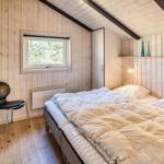 Schlafzimmer mit Bett, Stuhl und Fenster. Holzwände und Dachschräge.