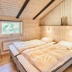 Schlafzimmer mit Doppelbett, Fenster und Holzwandverkleidung.