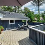 Terrasse mit Liegestühlen und Sonnenschirm neben einem blauen Holzhaus.