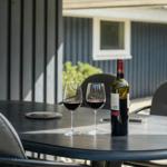Runder Tisch mit zwei Gläsern und einer Flasche Wein auf der Terrasse.
