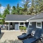 Terrasse mit Liegestühlen und Sonnenschirm vor einem blauen Haus mit Dach