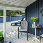 Terrasse mit zwei Stühlen, Tisch und Liegestuhl. Wand mit Hirschgeweih und Kranz.