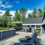 Terrasse mit Liegestühlen und Sitzbereich unter einem Sonnenschirm. Hintergrund: Wald und blauer Himmel.
