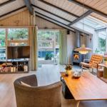 Wohnzimmer mit Holzboden, Kamin und großem Fensterbereich.