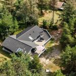 Haus mit Terrasse und Grillplatz im Wald. Parkplatz mit Fahrzeugen.